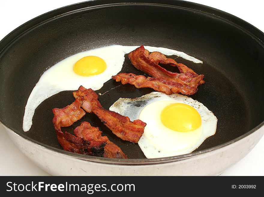 Shot of fried eggs & bacon in skillet upclose