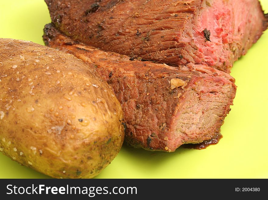 Shot of a baked potato & grilled steak upclose