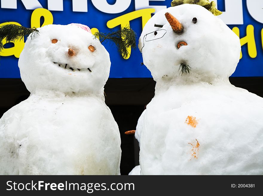 Two amusing snow-mans with glasses and carrots