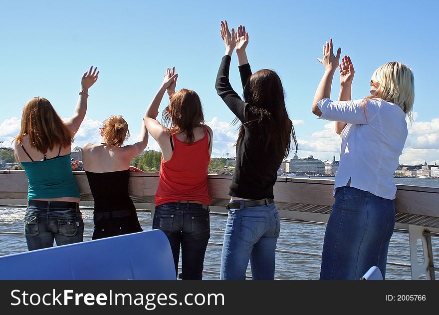 Five happy girls dancing on a boat