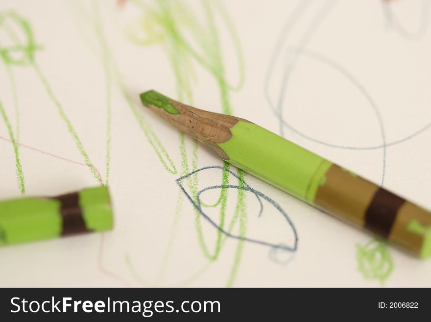 Crayons lie on a child's drawing. Crayons lie on a child's drawing