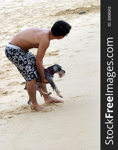 The man holding a wet dog (fox terrier) on the beach. The man holding a wet dog (fox terrier) on the beach