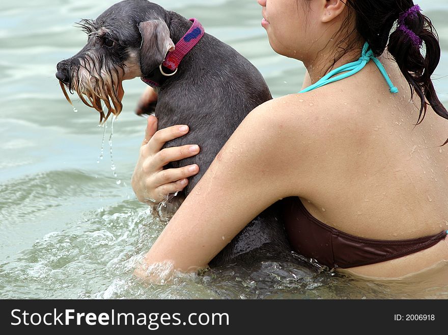 The girl swimming with a fox terrier in the ocean. The girl swimming with a fox terrier in the ocean