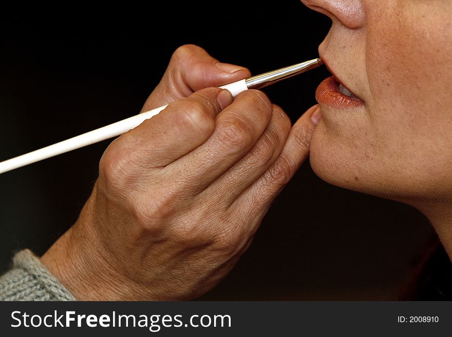 Makeup artists at work, coloring lips of a woman