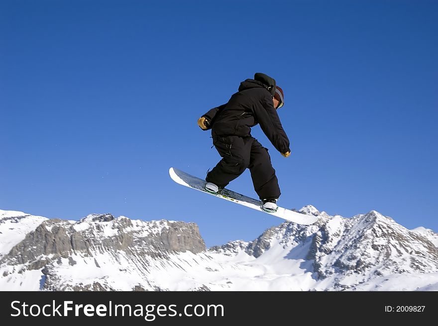 A snowboarder jumping high through a blue sky. A snowboarder jumping high through a blue sky