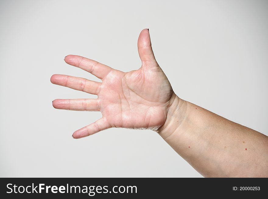 A woman holding her arm out and showing all of her fingers against a white background. A woman holding her arm out and showing all of her fingers against a white background.
