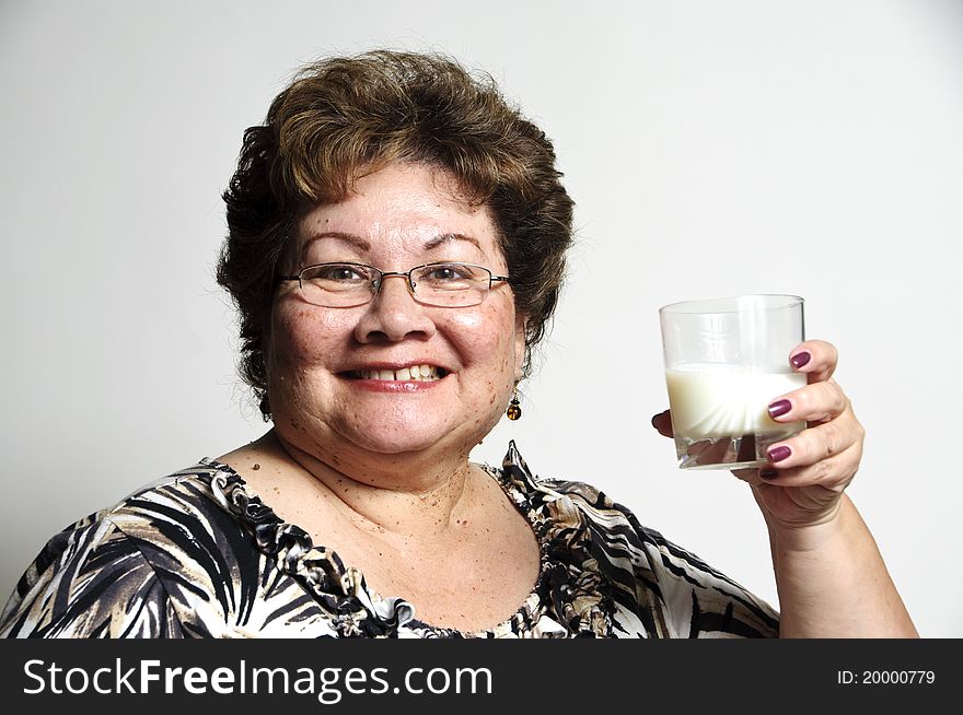 An older Hispanic woman holding a glass of milk. An older Hispanic woman holding a glass of milk.