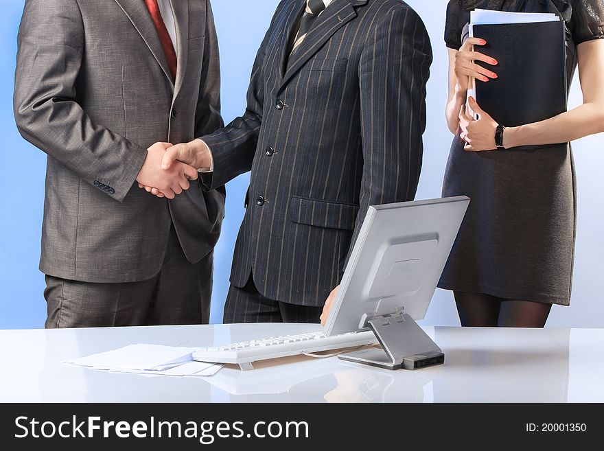 Business team of three people, two men shaking hands.