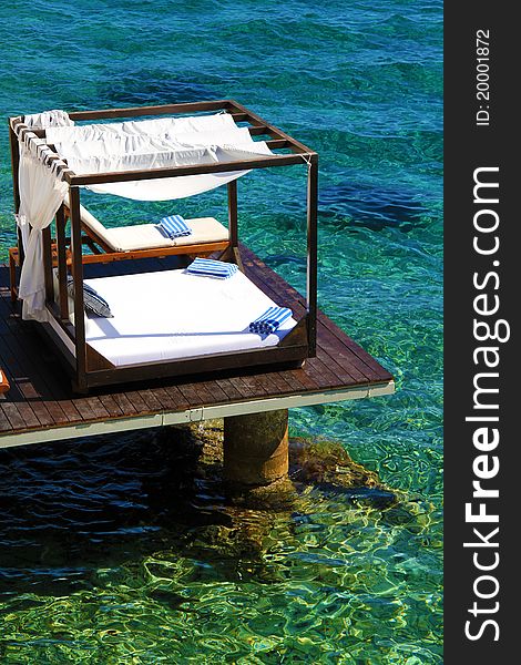 Luxury beds with flowing curtains over tropical water. Luxury beds with flowing curtains over tropical water.