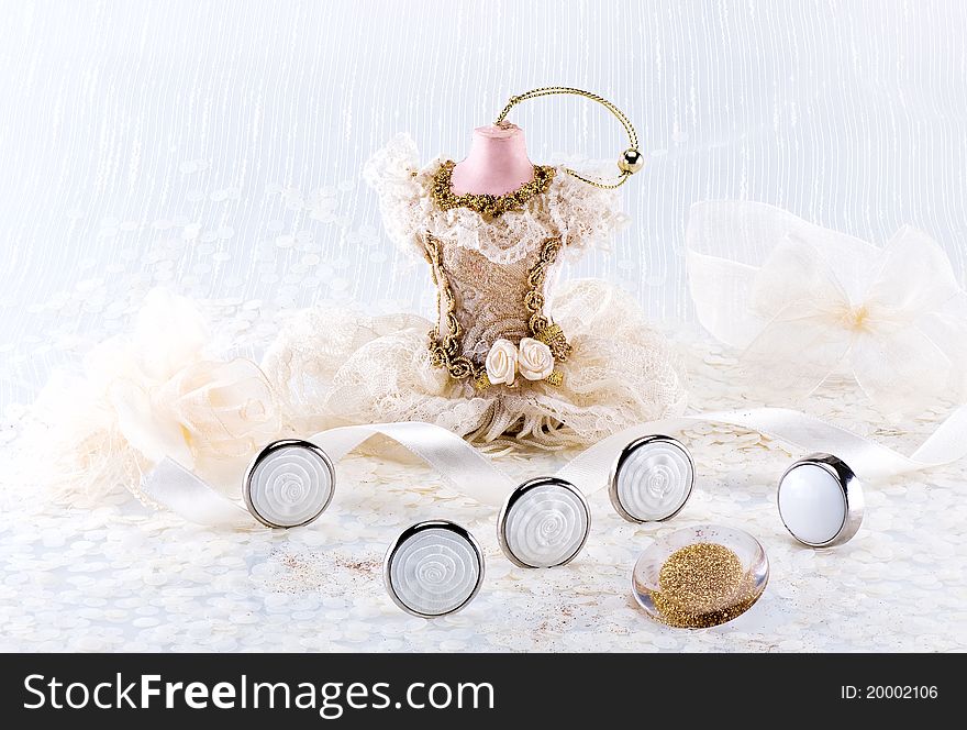 Wedding still life with buttons, satin ribbon, statue in dress