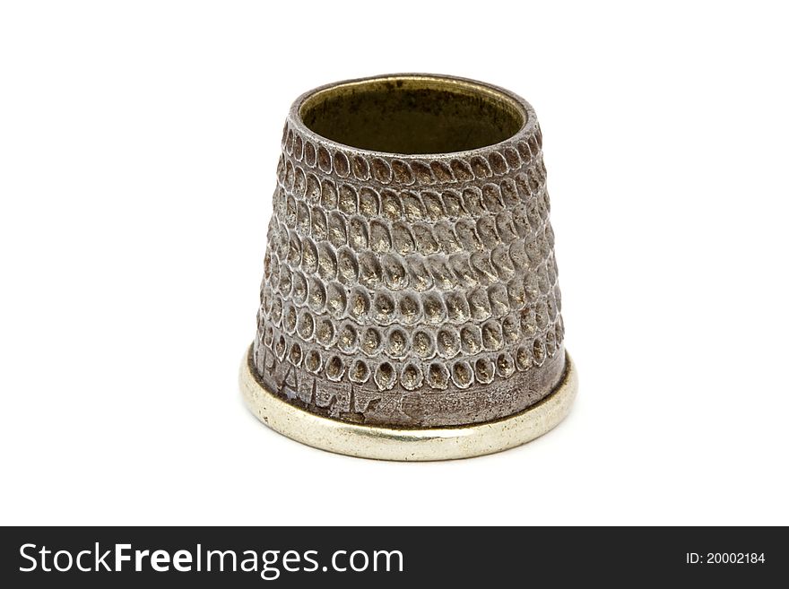 Close up of an old silver thimble over white