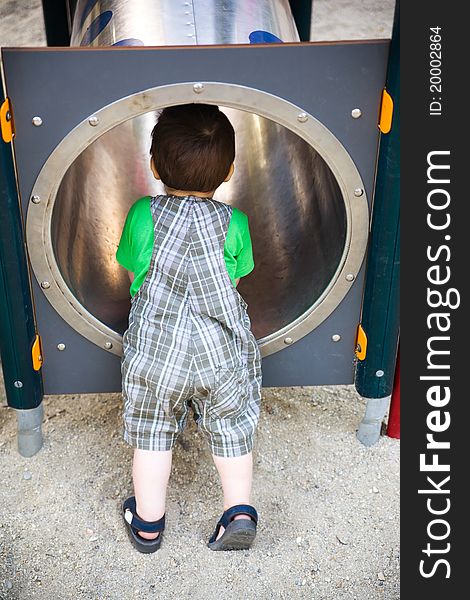 Child exploring a pipe tunnel in playground. Child exploring a pipe tunnel in playground