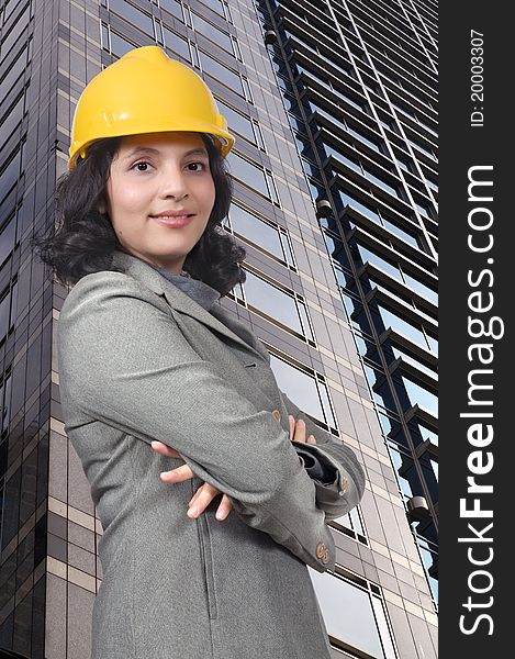 Successful woman wearing yellow helmet, smile in front of building. Successful woman wearing yellow helmet, smile in front of building