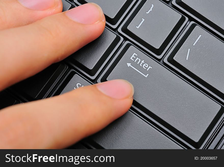 Left hand fingers pressing on black Enter key on computer keyboard. Left hand fingers pressing on black Enter key on computer keyboard.