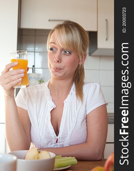 Young blond woman with her breakfast at a table in a kitchen