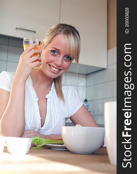 Young blond woman with her breakfast at a table in a kitchen