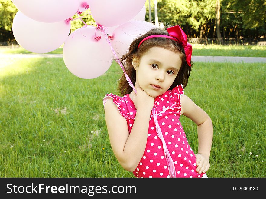 Close-up of a little girl standing in the park with pink balloons. Close-up of a little girl standing in the park with pink balloons