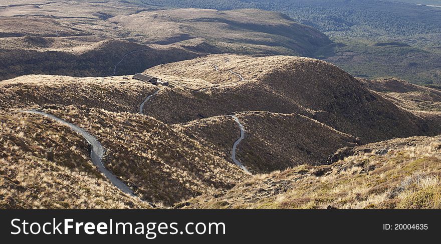 Twisting hilly track from mountain down to hut on sunset. Twisting hilly track from mountain down to hut on sunset