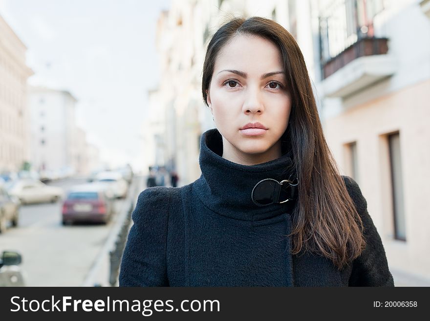 A beautiful woman in the coat standing on the street.