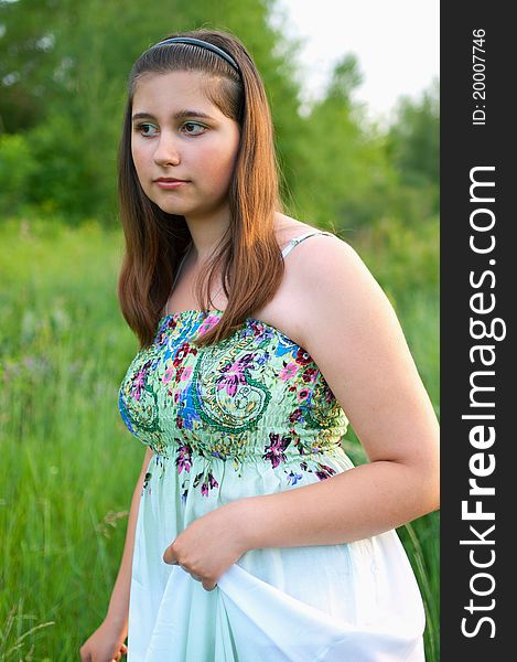 The portrait of beautiful young girl in light dress on a the summer green background