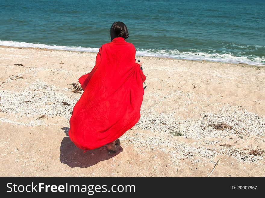 Girl in big red pareo walking on the beach. Girl in big red pareo walking on the beach