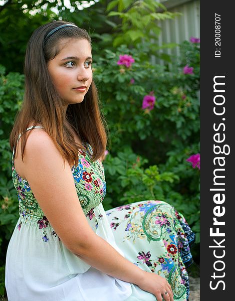 Young beautiful girl against bush of dogrose. Shallow DOF