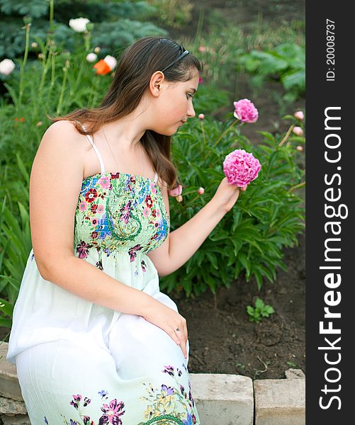 Young beautiful girl against pink peony flowers. Shallow DOF