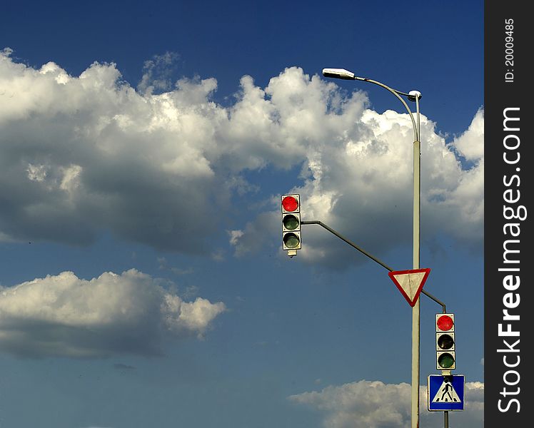 Stoplight against the sky with clouds