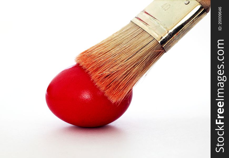 A brush painting a red easter egg. A brush painting a red easter egg