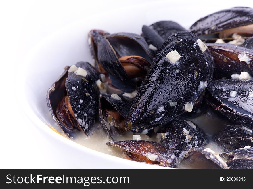 Close up picture of mussels in the bowl in white background.