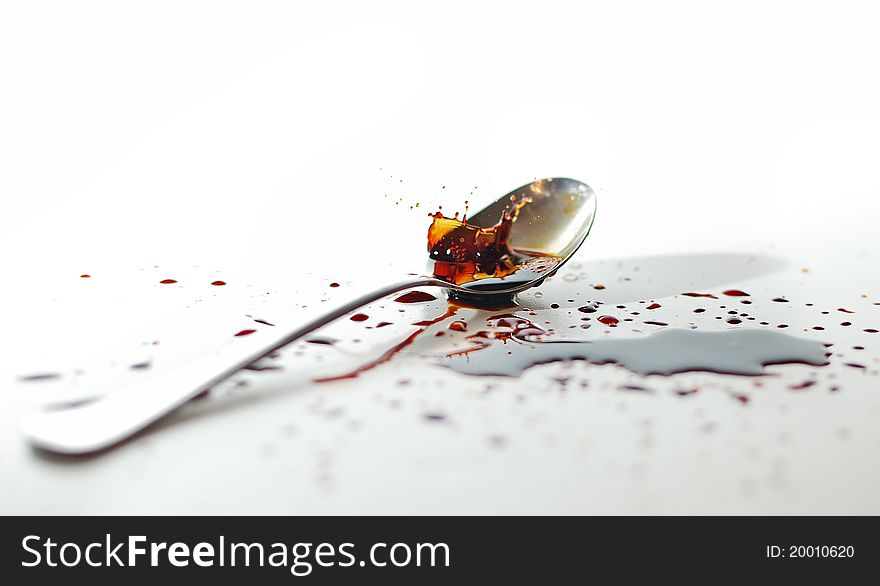 Splash with color over the spoon on white table. Splash with color over the spoon on white table