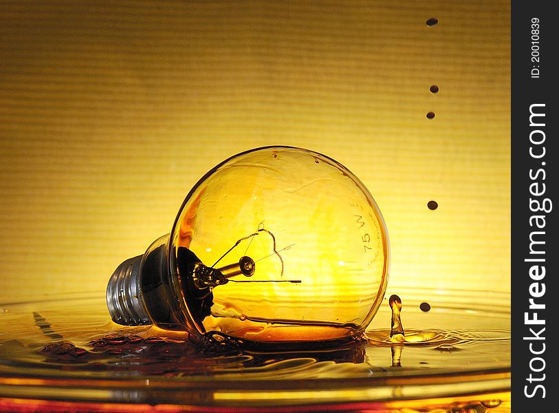 Splash with color over the bulb in the bowl filled with water. Splash with color over the bulb in the bowl filled with water