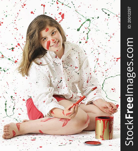 An attractive preteen girl painting red in a white shirt and background spashed in Christmas colors. An attractive preteen girl painting red in a white shirt and background spashed in Christmas colors.