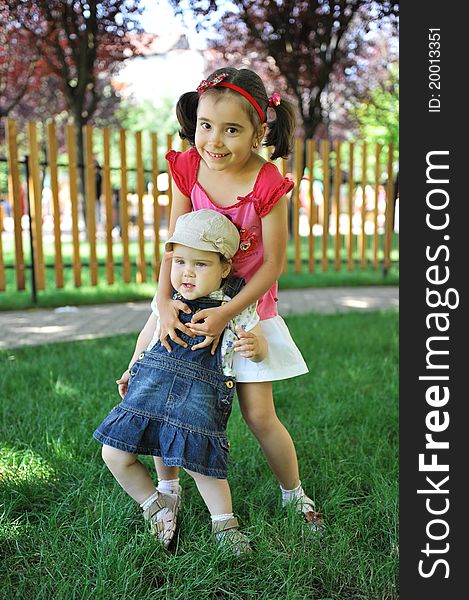 Two sisters sitting outdoors smiling and hugging. Two sisters sitting outdoors smiling and hugging