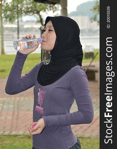 Young woman drinking water after exercise