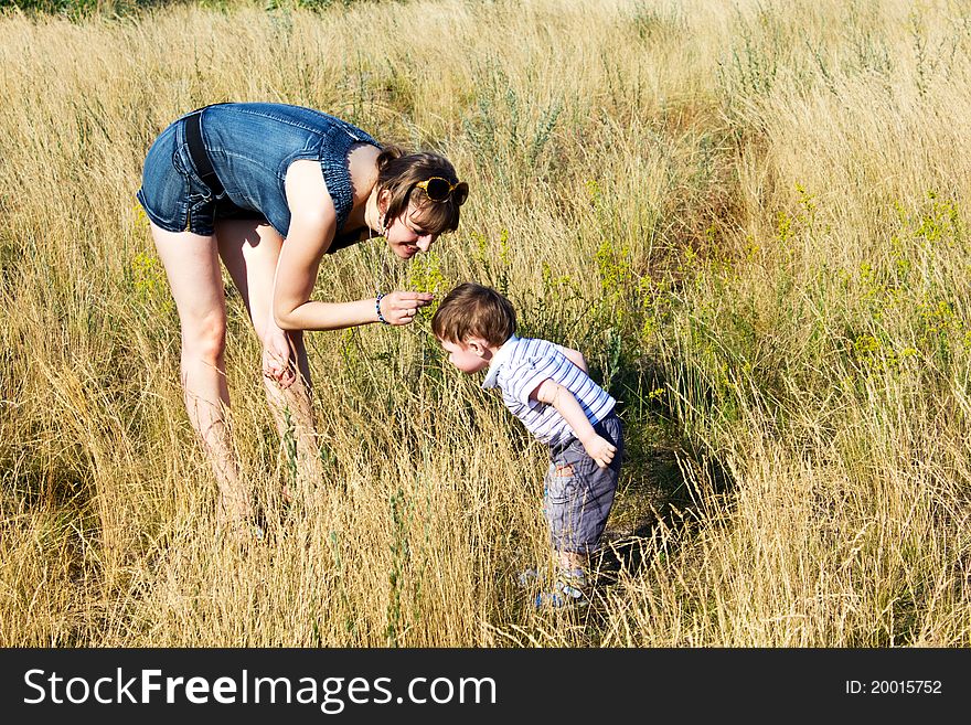 A mother plays with a son among fragrant herbage. A mother plays with a son among fragrant herbage