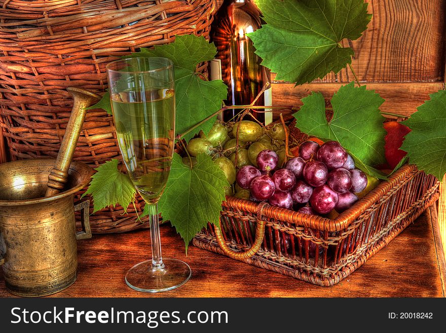 Glass of wine, wicker basket with grapes, grapevine,mortar on wooden background. Glass of wine, wicker basket with grapes, grapevine,mortar on wooden background.