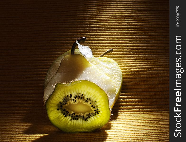Fruits - kiwi, apple and pear on the table with yellow background
