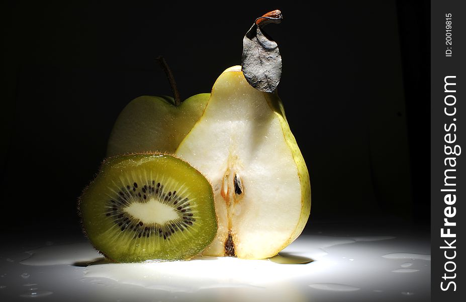 Fruits - kiwi, apple and pear on the table with dark background