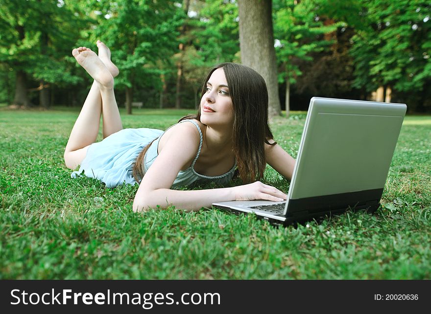 Beautiful woman lying on a green meadow and using a laptop. Beautiful woman lying on a green meadow and using a laptop