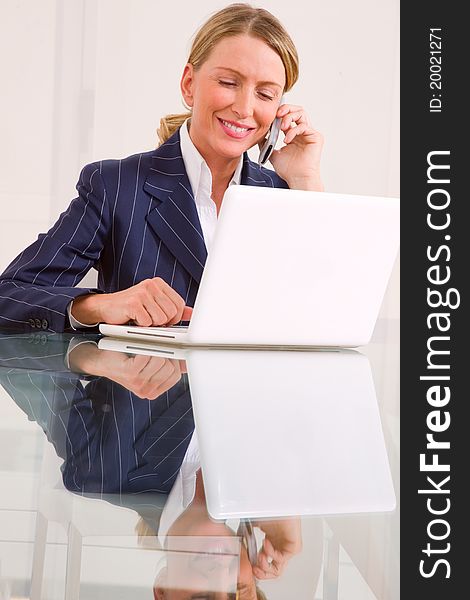 Businesswoman in office with mobile and laptop