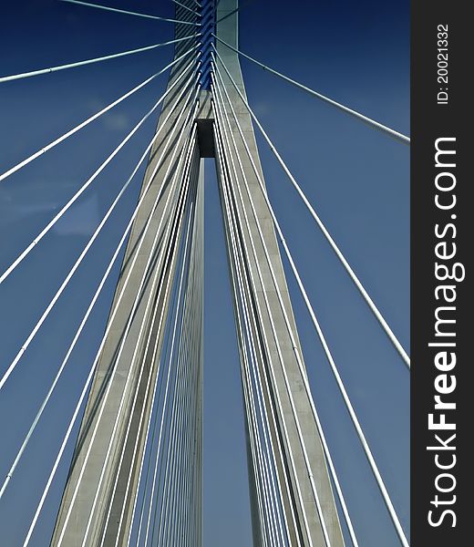 Suspension cables at modern highway bridge against clear blue sky at sunny summer day.