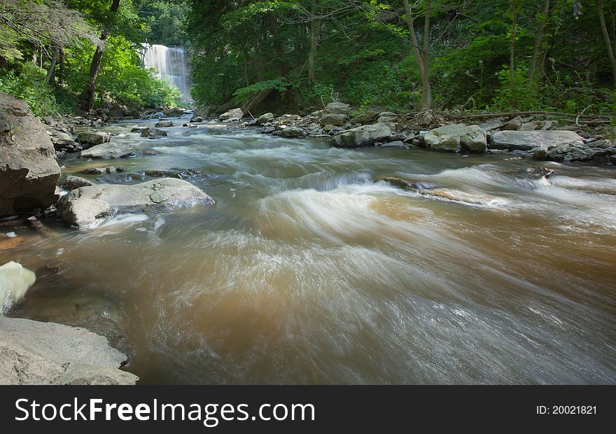 Fast moving river with waterfall in the background.