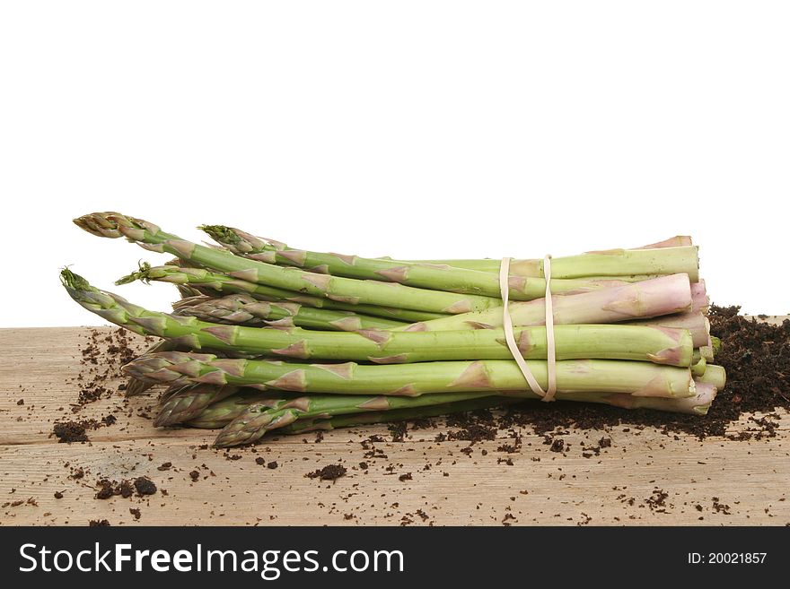 Bunch of freshly picked asparagus spears on a wooden board with residual soil