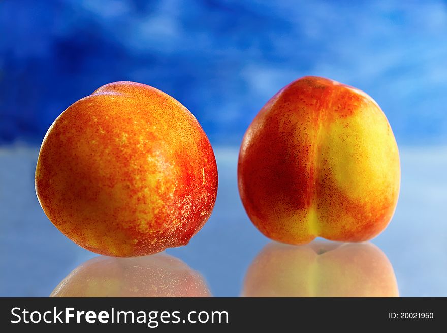 Two nectarine with blue background.