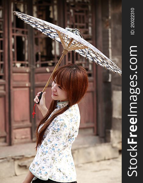 Happy Chinese girl holding the umbrella posing outdoor.