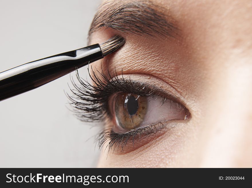Woman applying eye make-up with brush on white background. Woman applying eye make-up with brush on white background