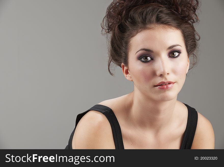 Portrait of beautiful young woman with make-up on grey background