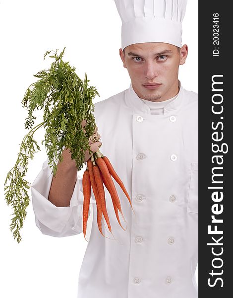 The young chef in uniform and chef's hat holding a bunch of carrots.