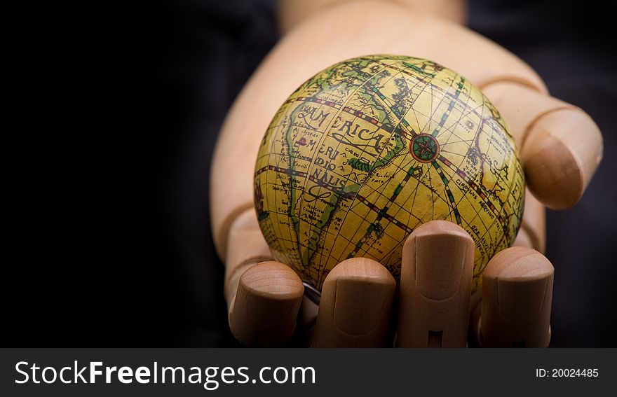 Global in wooden hand, on black background